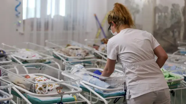 В одному з перинатальних центрів Харкова медсестра стоїть поруч із ліжками, в яких лежать закутані немовлята