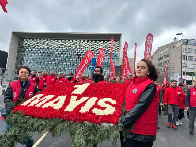 disk heyeti, üstünde 1 mayıs yazan bir çelenkle yürürken