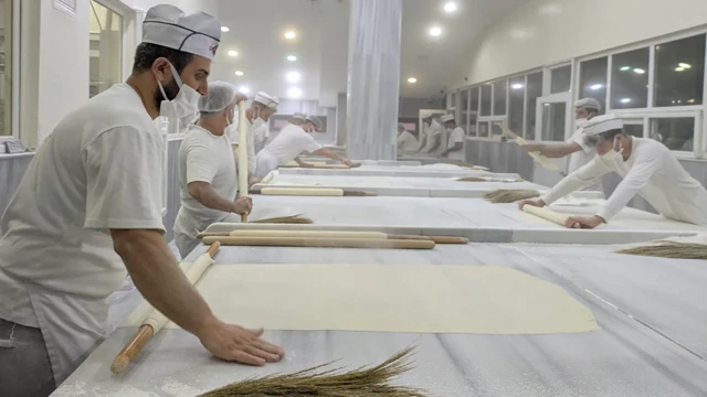 خباز يقوم بفرد العجين إلى صفائح رقيقة لصنع البقلاوة