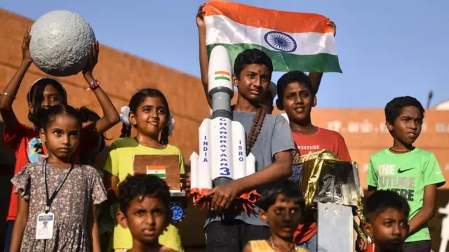 एउटा प्रतिकृति बोकेर भारतले प्रक्षेपण गरेको चन्द्रयान-३ हेर्दै भारतीय बालबालिकाहरू। उक्त भारतीय अन्तरिक्षयान चन्द्रमाको दक्षिणी ध्रुवमा सफलतापूर्वक अवतरण गरेको थियो। 