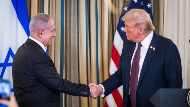 US President Donald Trump (R) shakes hands with Israeli Prime Minister Benjamin Netanyahu (L) in front of their respective national flags in the White House on 29 Sep 2025