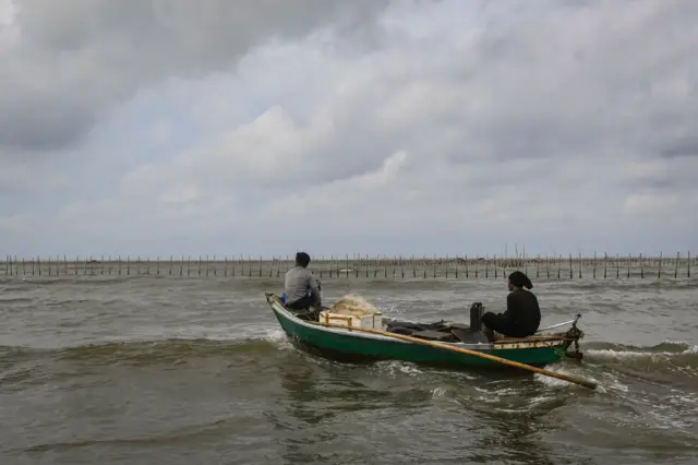 Nelayan melintas di dekat pagar laut di kawasan pesisir di Kabupaten Tangerang, Banten, Kamis (9/1).