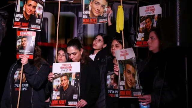 人質の写真が印刷されたプラカードを掲げる家族