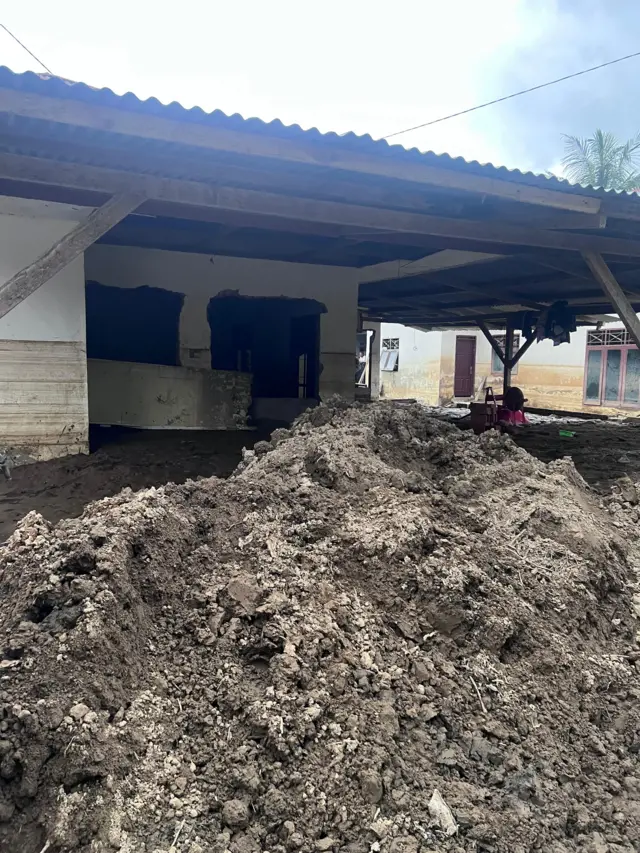 Salah satu rumah warga di Meureudu, Pidie Jaya, pada Rabu (18/02) yang masih tertimbun lumpur. Warga harus membersihkan sendiri tumpukan lumpur yang telah mengeras itu. 