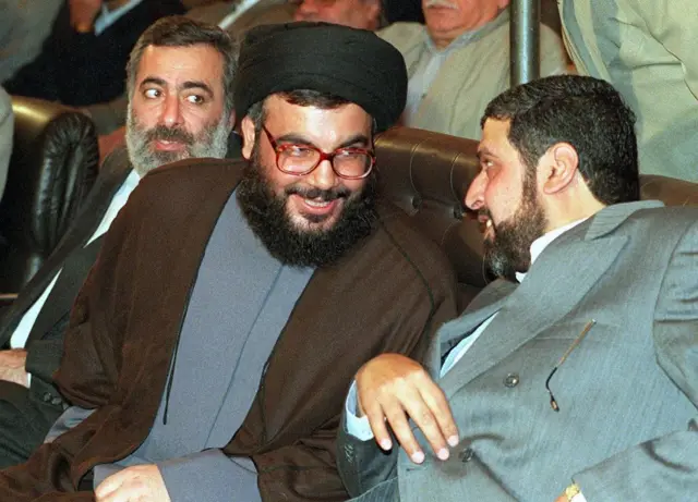 أمين عام حزب الله حسن نصر الله يتحدث إلى الأمين العام لحركة الجهاد الإسلامي رمضان عبد الله شلح (يمين) والى جانبهما سفير إيران إلى سوريا حسين شيخ الإسلام، يوم 29 أكتوبر/تشرين الأول 1999.