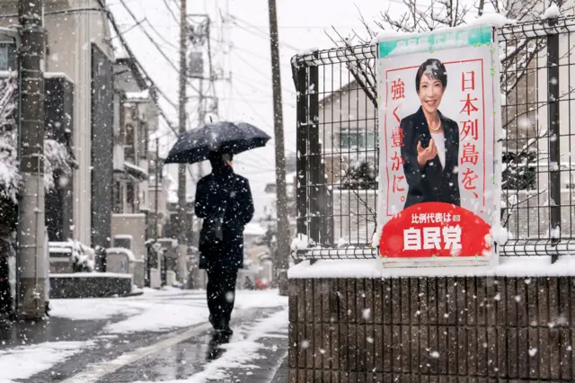  A pedestrian walks past an election poster bearing a photograph of Japanese Prime Minister and Liberal Democratic Party (LDP) President Sanae Takaichi displayed near a polling station on February 08, 2026 in Tokyo, Japan. Voters across the country headed to polls today as Japan's Lower House election was held