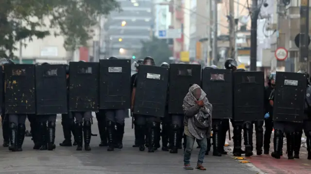 Homem se protegendo na frentesuperbet apostasbarreirasuperbet apostaspoliciais com escudos, na Cracolândia