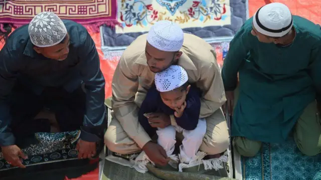 ثلاثة رجال وطفل صغير يجلسون على سجادة صلاة.