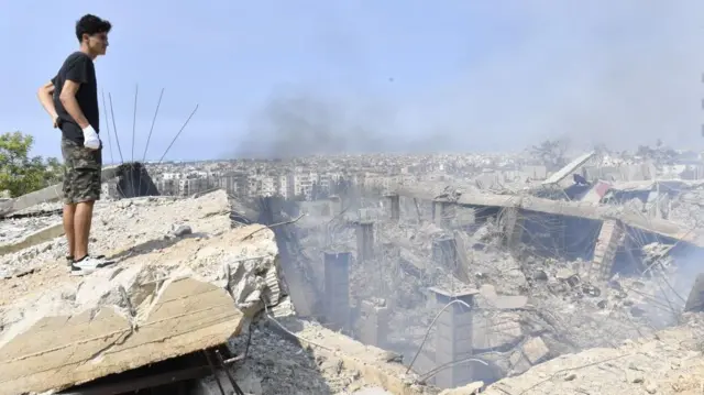 दक्षिण पूर्वी बेरूत में इसराइली हवाई हमले के बाद के मंज़र को देखता एक शख़्स