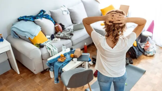 Mulherdicas e palpites futebolcostas com as mãos atrás da cabeça olhando para casa bagunçada