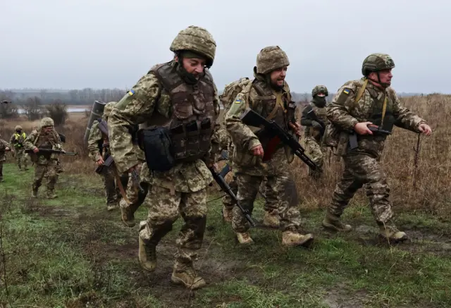 Група солдат ЗСУ з автоматами йде полем