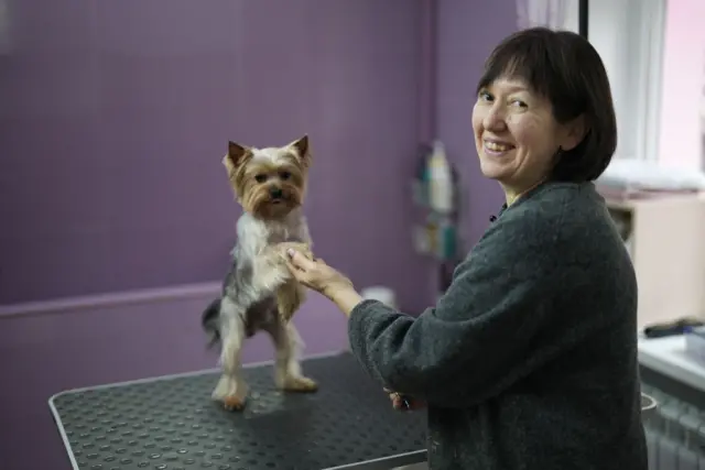 Žena drži psa za prednje šape