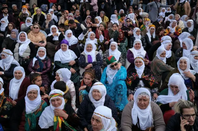 Fotoğrafta 50'den fazla kadın görülüyor. Oturmuşlar, bazıları zafer işareti yapıyor.