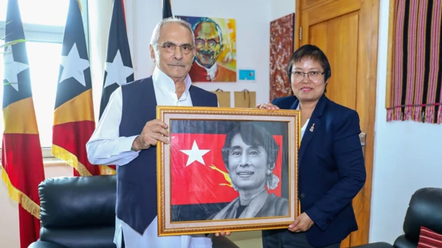  တီမောလက််စ်တေ သမ္မတနဲ့ NUG နိုင်ငံခြားရေးဝန်ကြီး ဒေါ်ဇင်မာအောင်တို့ တီမောနိုင်ငံမှာ တွေ့ဆုံခဲ့မှု။ ဒေါ်အောင်ဆန်းစုကြည်ရဲ့ပုံ ပါတဲ့ ပန်းချီကားကို နှစ်ယောက် ကိုင်ထားပြီး သမ္မတရော ဒေါ်ဇင်မာအောင်တို့ပါ ကင်မရာကို ပြုံးပြီးကြည့်နေကြ 