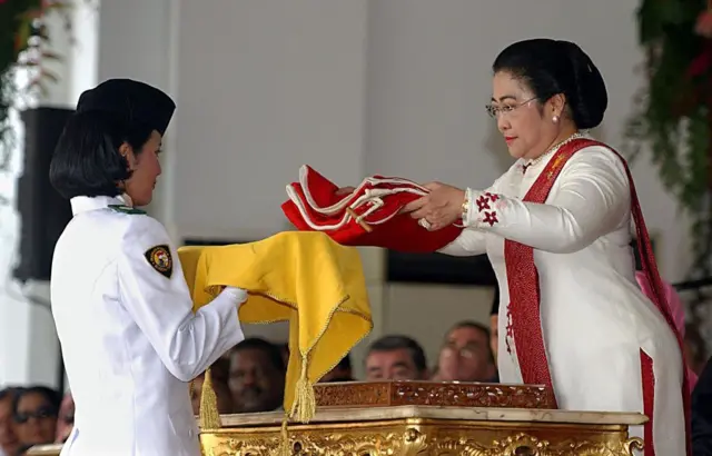 Presiden Megawati Sukarnoputri (kanan) menyerahkan bendera nasional kepada seorang pelajar dalam upacara peringatan hari kemerdekaan di Istana Kepresidenan di Jakarta, 17 Agustus 2003.