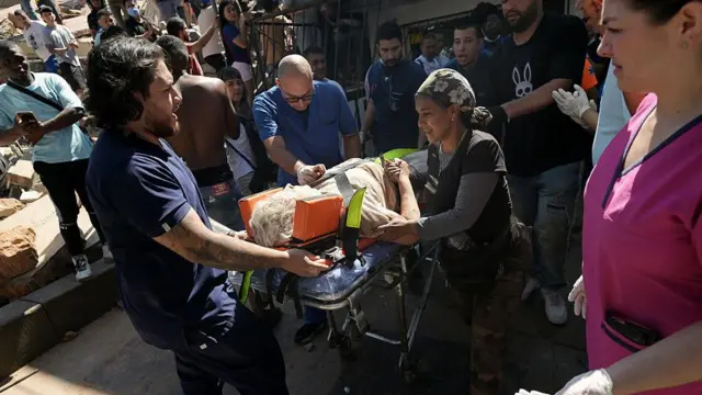 Uma mulher é carregada em uma maca após ser resgatada de um prédio que desabou devido ao terremoto em Cali.