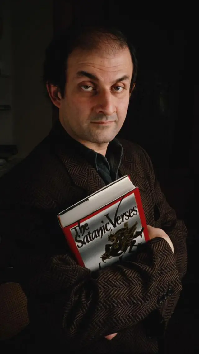 سلمان رشدی، نویسنده، در خانه اش در ایزلینگتون، در لندن، در حالی که نسخه ای از "آیات شیطانی" را در دست دارد ۲۸ دی ۱۳۶۹