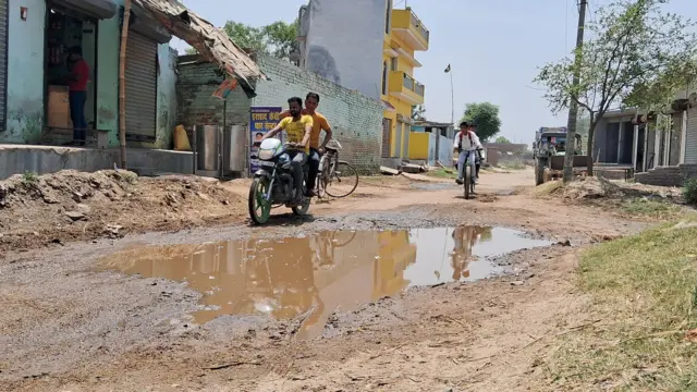 गडढ़ों से बचकर चलते स्कूल के छात्र