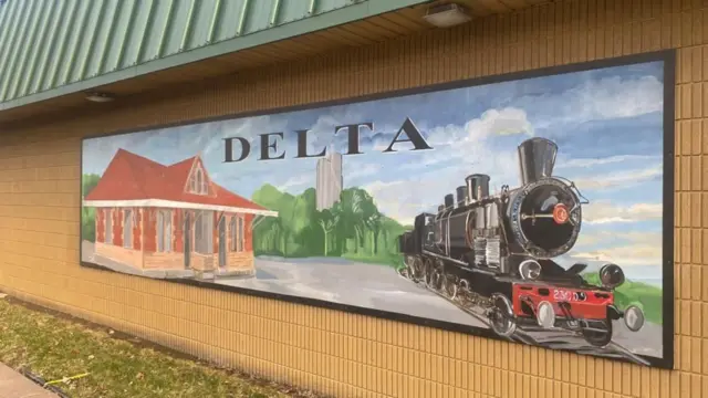 Un muro con un tren dibujado en un paisaje que dice Delta