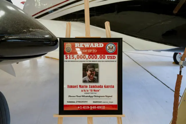 Un cartel que anuncia una recompensa por el exlíder del Cártel de Sinaloa, Ismael "El Mayo" Zambada, está colocado junto a una aeronave Beechcraft King Air, utilizada en julio de 2024 para trasladar a Zambada a Estados Unidos.