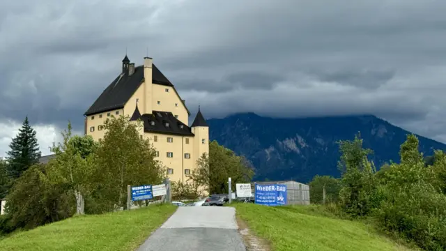 O castelo Schloss Goldenstein em um dia nublado, com os Alpes austríacos ao fundo