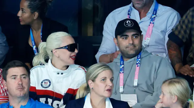 ဂါဂါဟာ အမေရိကန်အားကစားသမားတွေကို အားပေးတဲ့ ''Team USA'' ဆိုတဲ့ ဂျာကင်အင်္ကျီကို ဝတ်ဆင်ပြီး မိုက်ကယ် ပိုလန်စကီး(ညာဘက်အမျိုးသား)နဲ့ အတူ ရေကူးပြိုင်ပွဲကို ကြည့်ရှုခဲ့