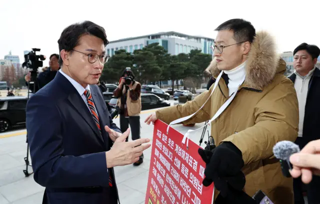 국회 앞에서 목에 호소문을 걸고 1인 시위 중인 김상욱 의원과 그와 대화하는 윤상현 의원