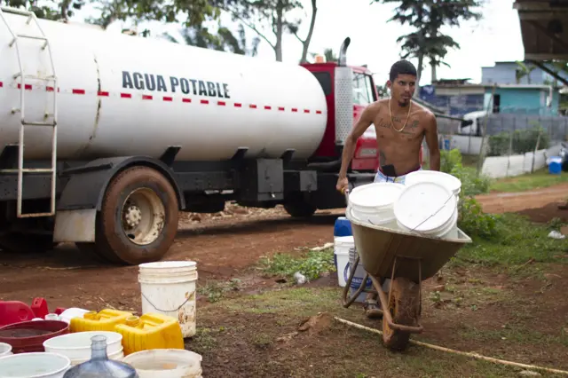 Joven cargando cubos de agua tras llenarlos en cisterna
