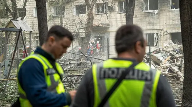 د اوکرایین لومړني مرستندویان یو مړی لیږدوي چې د اوکرایین په کېیف کې د روسیې د توغندي تر مستقیم برید وروسته له کنډوالو لاندې شوی و. دغلته د جون په میاشت کې د مستقیم توغندي د برید له امله ټوله ودانۍ ونړېدله.