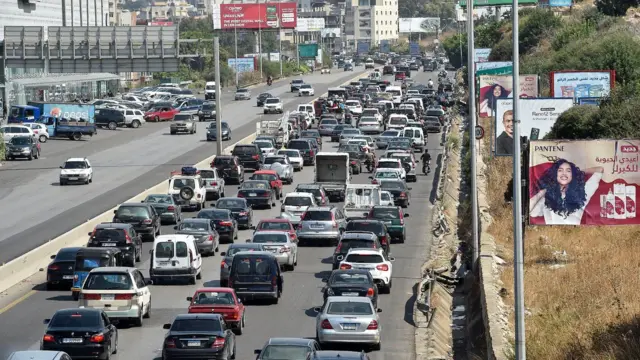 Foto de uma rodovia engarrafada por vários carros. 