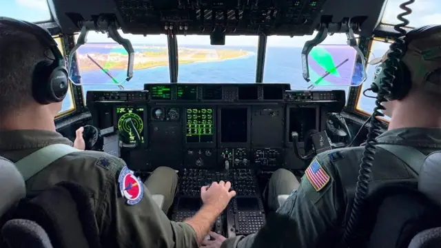 Cabine de comando de avião se preparando para pousar nas ilhas Marshall, com o comandante do 53° Esquadrão de Reconhecimento Climático, coronel Stephen Pituch, e o capitão Nate Wordal