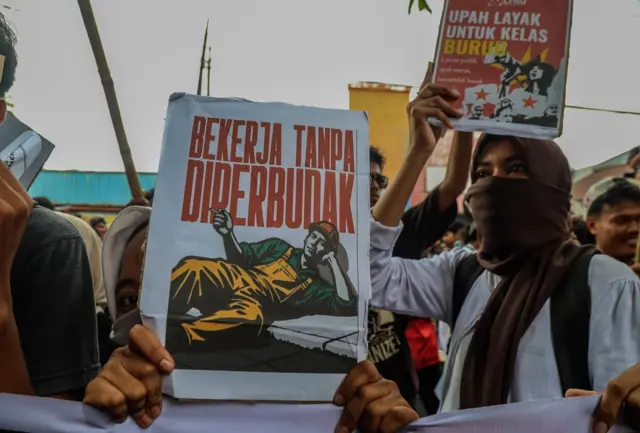 Sejumlah mahasiswa yang tergabung dalam Front Perjuangan Untuk Demokrasi membentangkan poster saat aksi memperingati Hari Buruh Internasional atau May Day 2026 di Kediaman Gubernur Malut, Ternate, Maluku Utara, Jumat (1/05).
