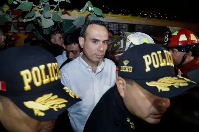 El presidente de Perú, José Jerí, tras dos policías, en una imagen nocturna. 