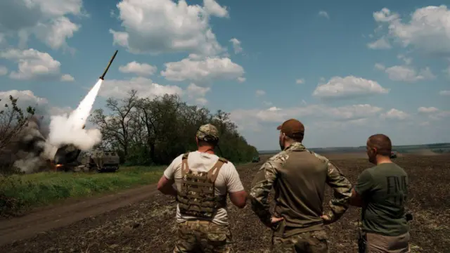 Українські військові спостерігають за тим, як M142 HIMARS запускає ракету на Бахмутському напрямку 18 травня 2023 року в Донецькій області, Україна