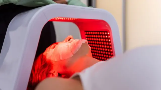 Mulher fazendo tratamento facial com luz LED em salão de beleza