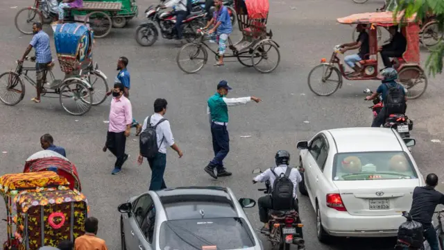 ছবিতে এক পুলিশ ট্রাফিক কন্ট্রোল করছে 