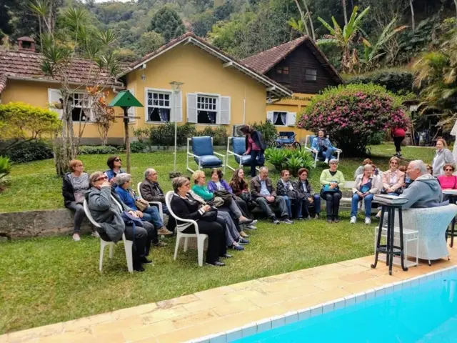 José Augusto Wanderley contando histórias para visitantes sentados à beira da piscina