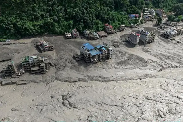 নেপালের নুয়াকোট জেলার ত্রিশুলি বাজারে আকস্মিক বন্যায় নদীর তীরবর্তী বাড়িঘর আংশিকভাবে ডুবে গেছে