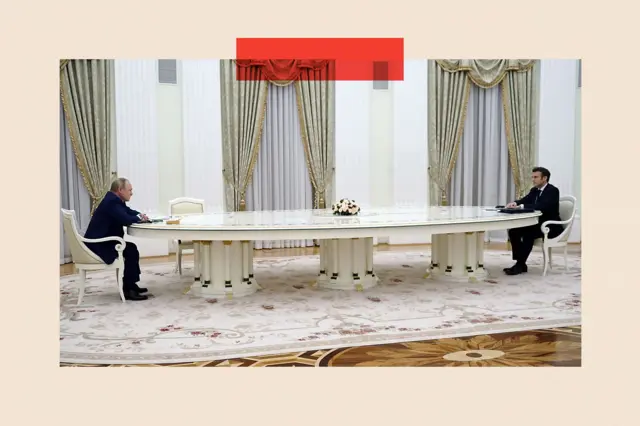 Prezydent Francji Emmanuel Macron (po prawej) w trakcie spotkania z przywódcą Rosji Władimirem Putinem w 2022 r. Siedzą po przeciwnych stronach bardzo długiego stołu. Na zdjęciu nie ma nikogo innego. 