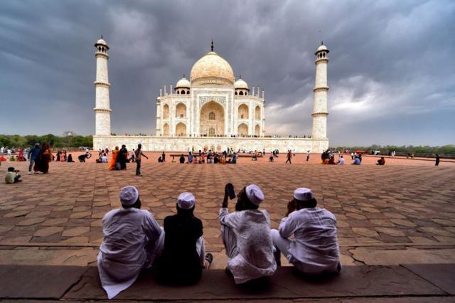 Visitantes muçulmanos observam o Taj Mahal 