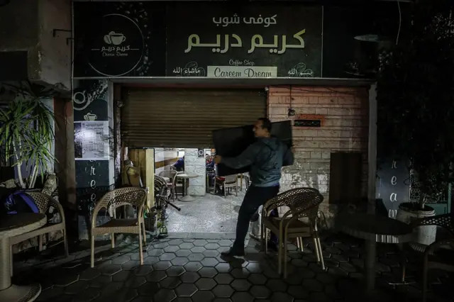 dükkanını kapatan bir adam, etrafta plastik sandalyeler var