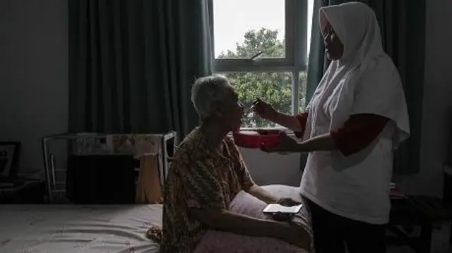 Seorang perawat memberi makan seorang nenek di sebuah flat pedesaan untuk orang tua di Sasana Tresna Werdha Ria Pembangunan di Cibubur, Jakarta Timur, Indonesia pada 3 Mei 2018.