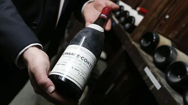 一名男子手持一瓶非常昂貴的勃根地紅酒