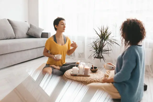 Two Woman sitting and drinking coffee after workout session at home.