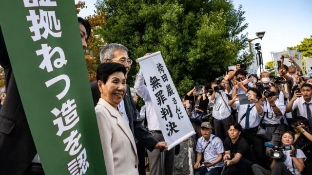 Hideko Hakamata (tengah) dan pengacara berpose dengan spanduk putih (kanan) bertuliskan "Iwao Hakamata tidak bersalah" saat meninggalkan Pengadilan Distrik Shizuoka di Shizuoka pada 26 September 2024.