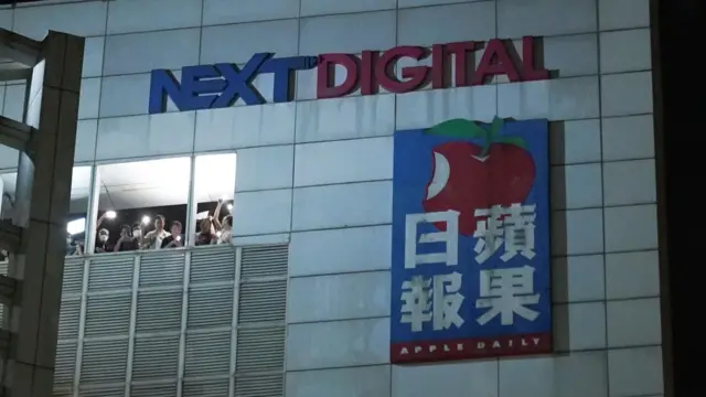 黑夜中一群香港《苹果日报》记者在将军澳壹传媒大楼楼顶挥舞手机电筒向门外支持者致意（23/6/2021）