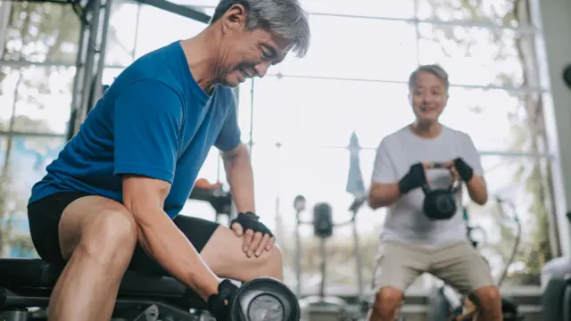 dois homens idosos treinando com pesos em academia