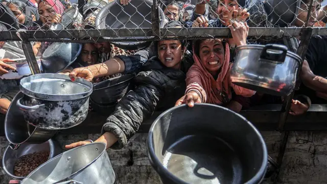 Mujeres desesperadas por comida extienden un cazo.