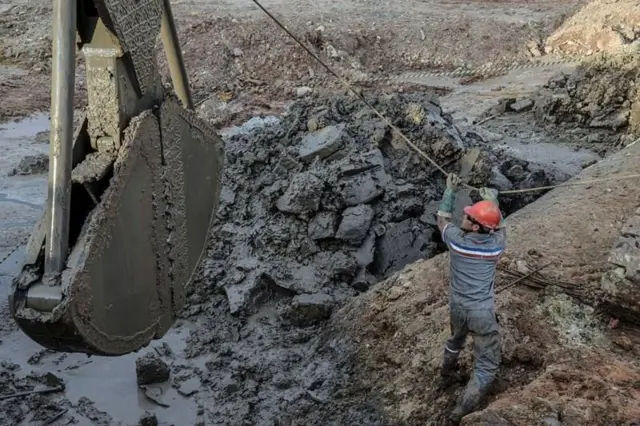 Homem uniformizado opera máquina em canteiro de obra.