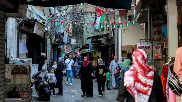 Pedestres caminhandonova plataforma de apostaviela com várias pequenas bandeiras palestinas penduradas